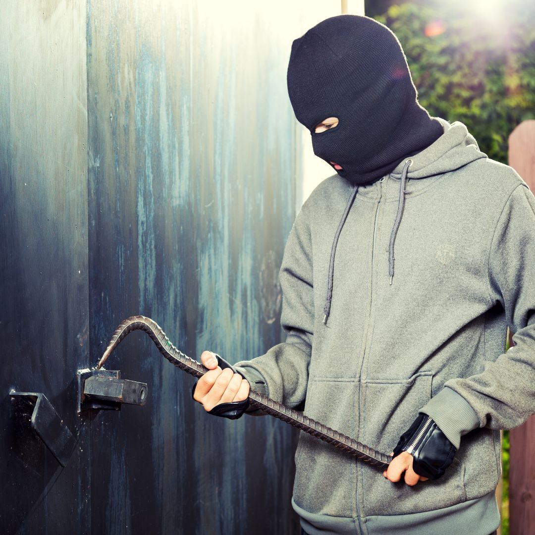 Burglar with crowbar breaking into garage